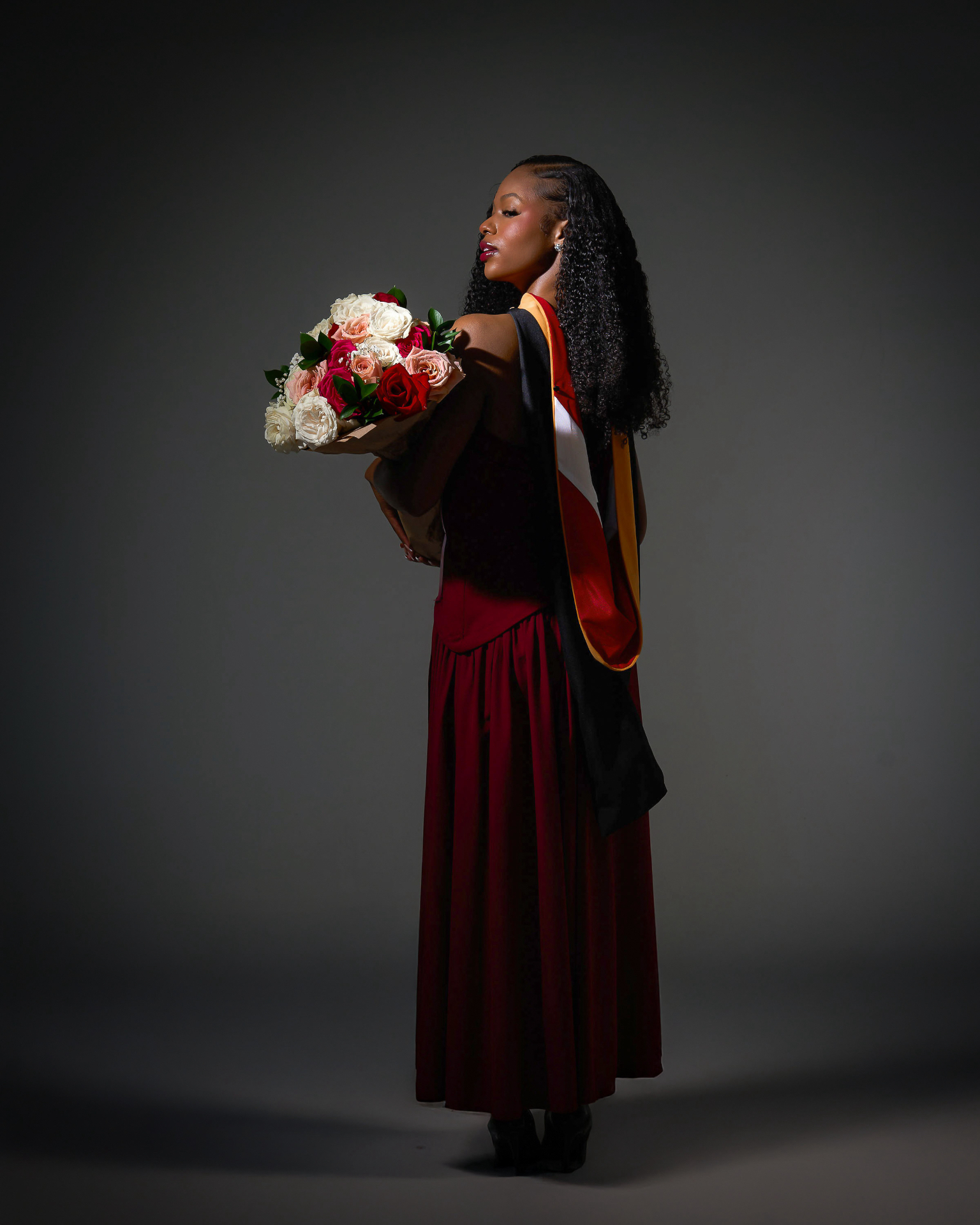 Dominique Killings in graduation regalia holding a bouquet of roses